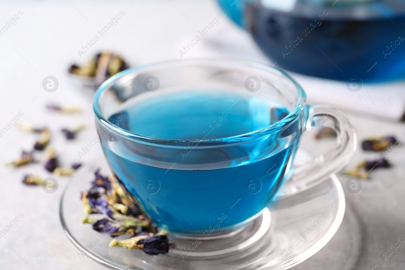 Photo of Glass cup of organic blue Anchan on light table, closeup. Herbal tea