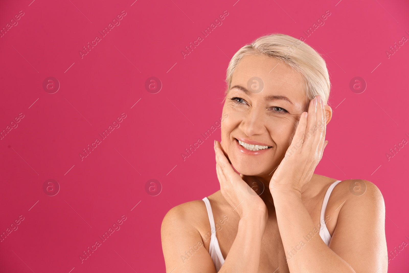 Photo of Portrait of beautiful mature woman on pink background. Space for text