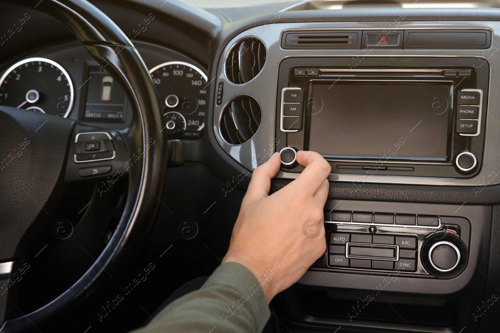 Photo of Listening to radio while driving. Man turning volume button on vehicle audio in car, closeup