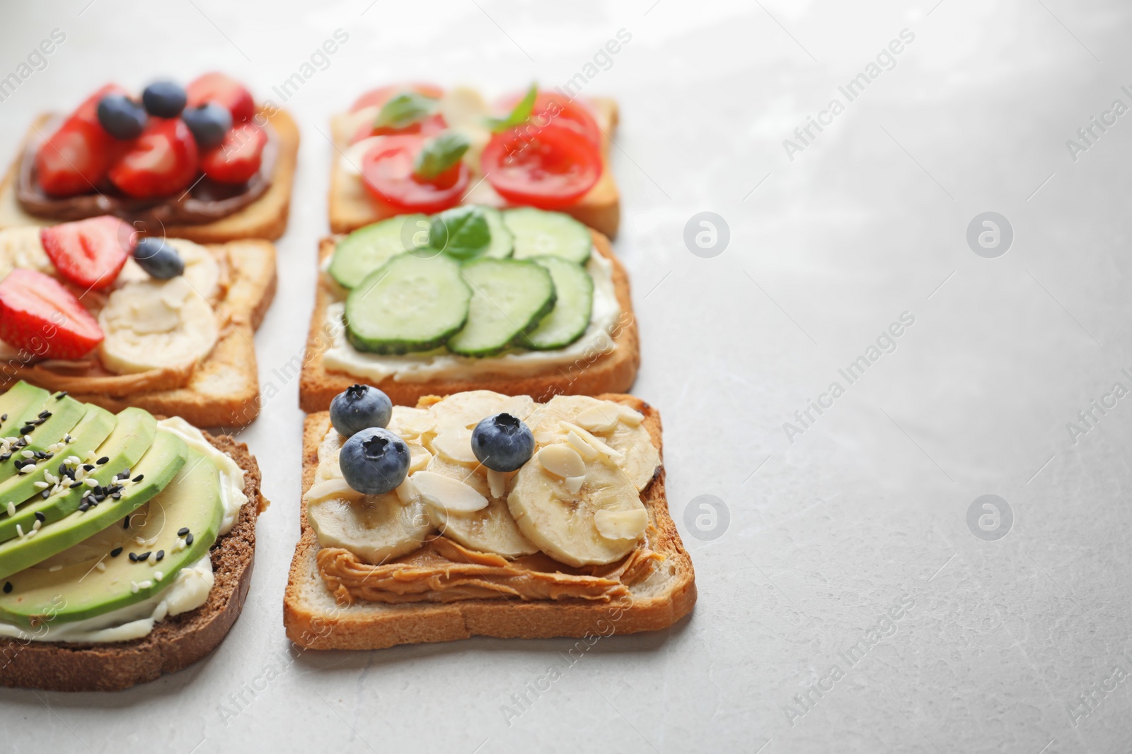 Photo of Tasty toast bread with fruits, berries and vegetables on light background, closeup