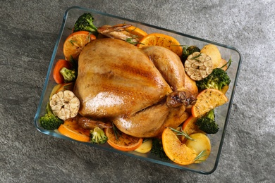Delicious chicken with oranges and vegetables on grey table, top view