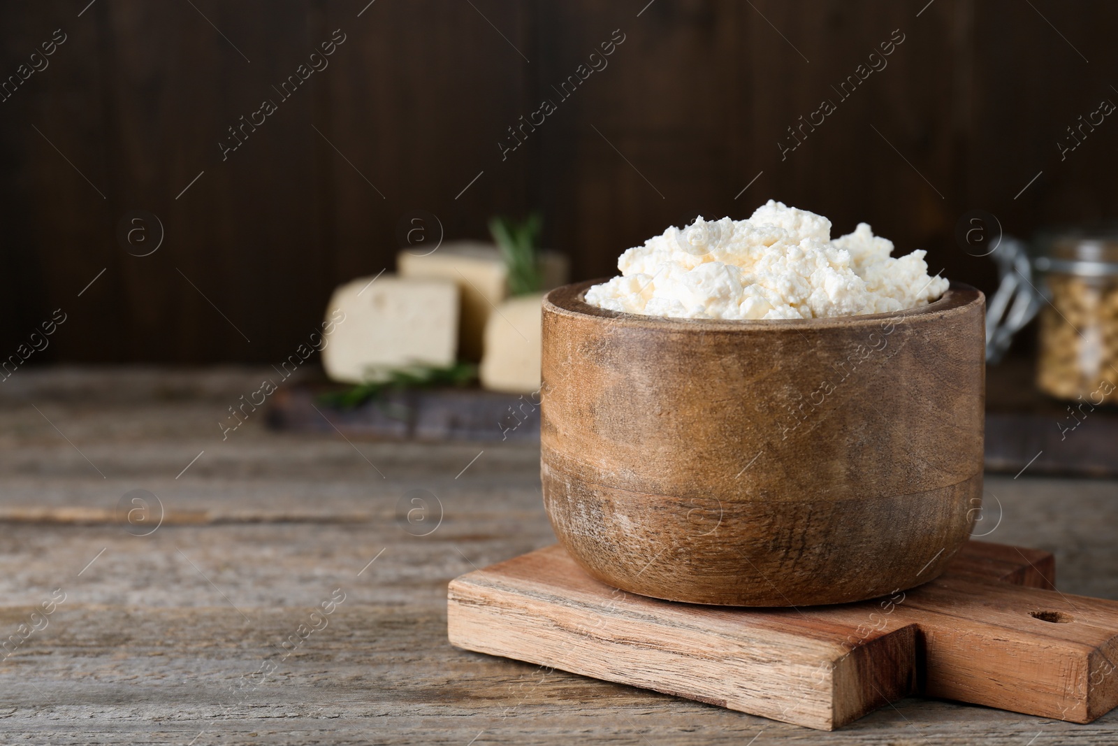 Photo of Delicious tofu cream cheese in bowl on wooden table, space for text