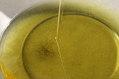 Photo of Pouring cooking oil into bowl, closeup view