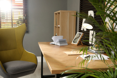 Photo of Comfortable workplace with wooden table and armchair