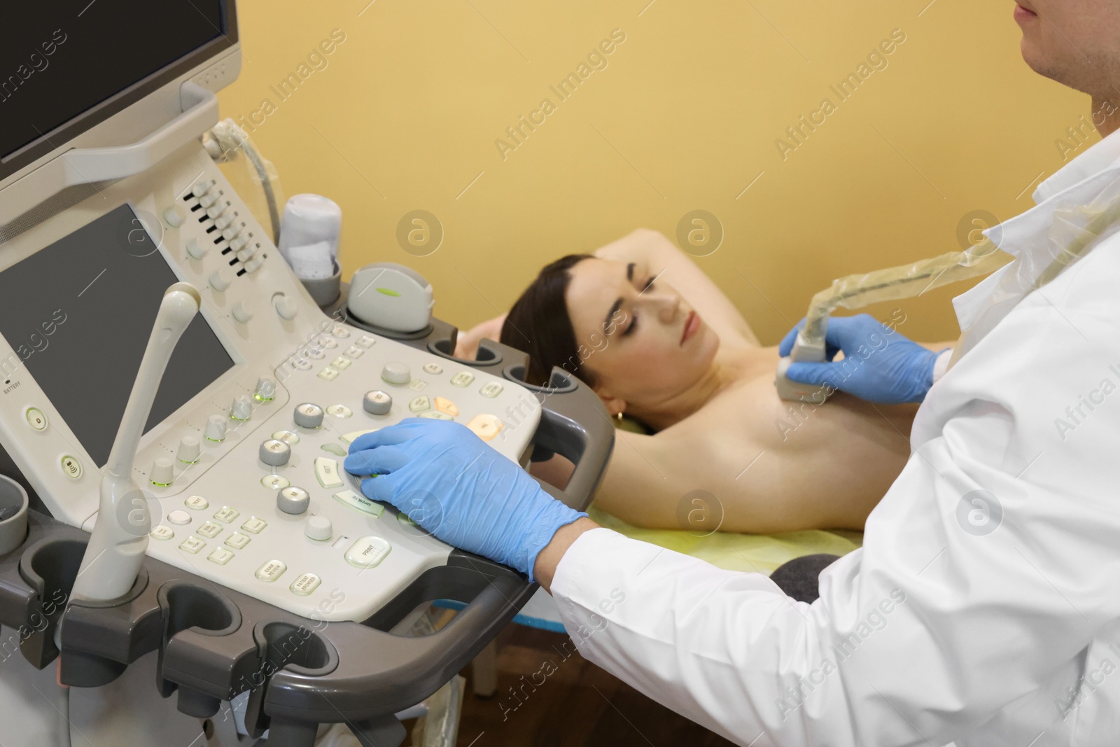 Photo of Mammologist conducting ultrasound examination of woman's breast in clinic, closeup