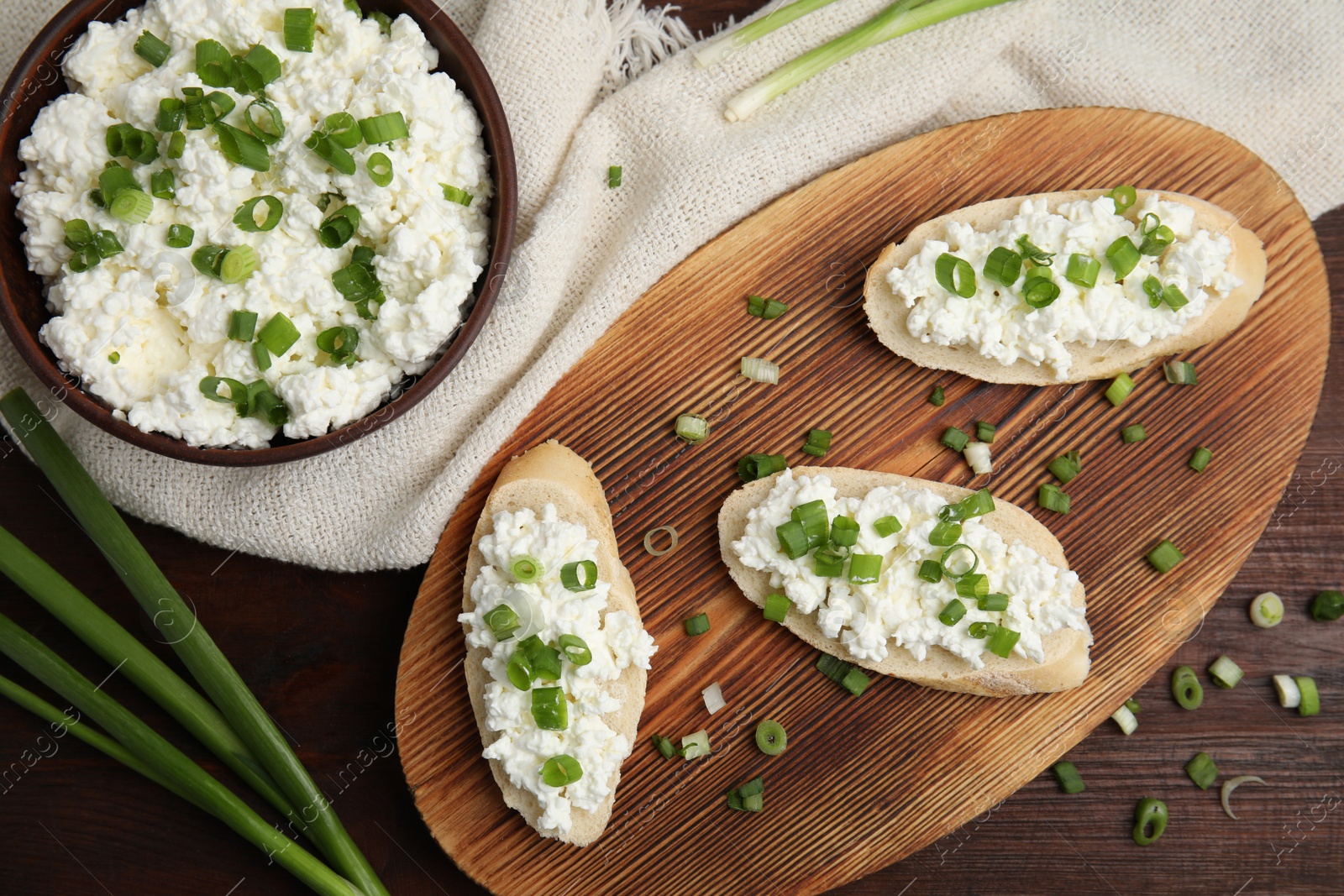 Photo of Bread with cottage cheese and green onion on wooden table, flat lay