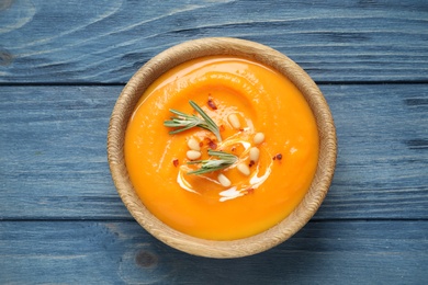 Delicious pumpkin soup in bowl on blue wooden table, top view