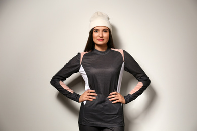 Photo of Woman wearing thermal underwear and hat on light grey background. Winter sport clothes