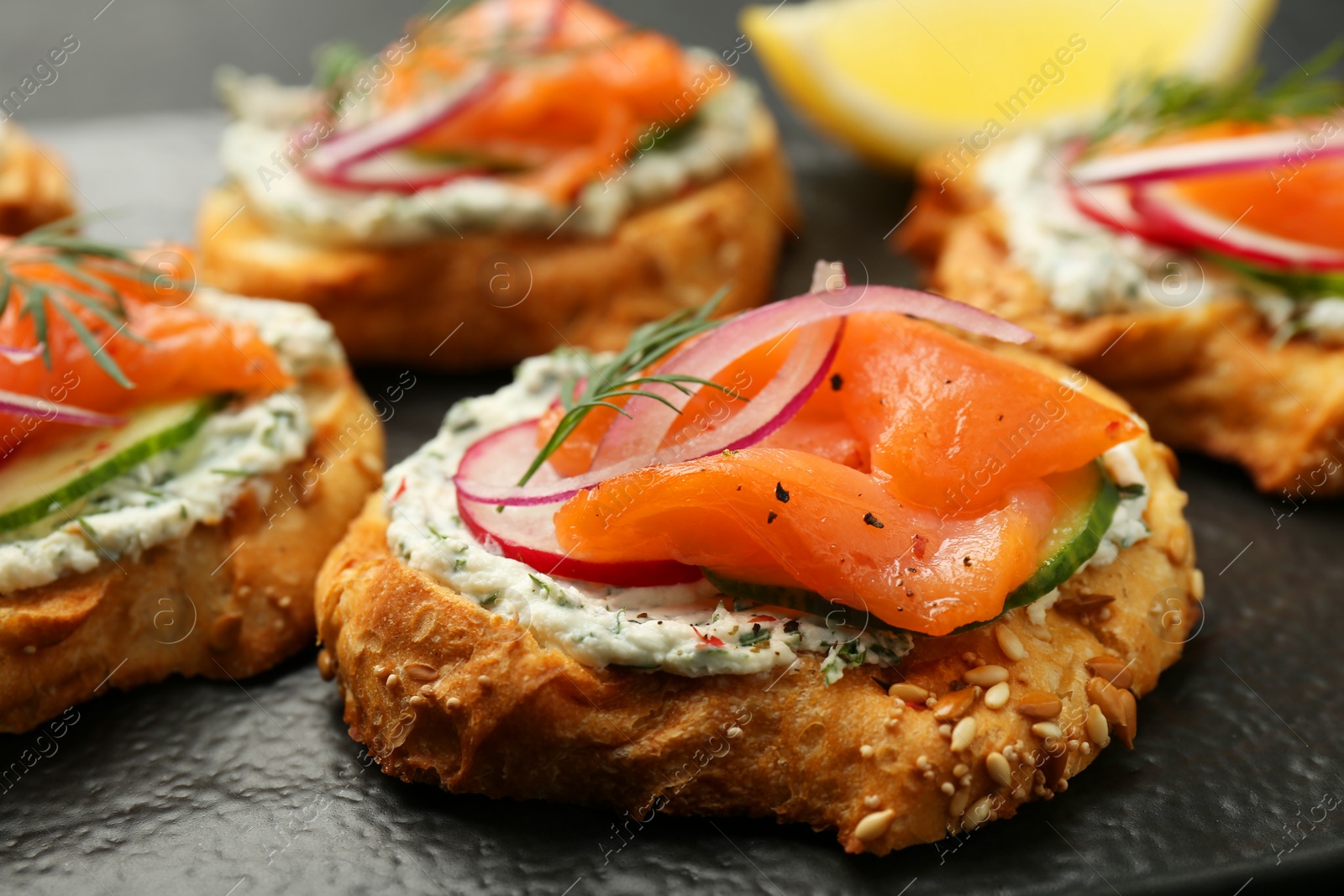 Photo of Tasty canapes with salmon, cucumber, radish and cream cheese on table, closeup