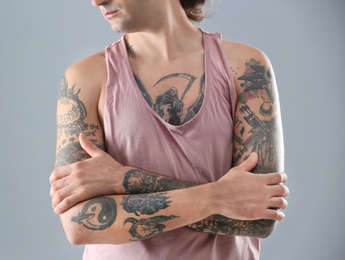 Photo of Young man with stylish tattoos on grey background