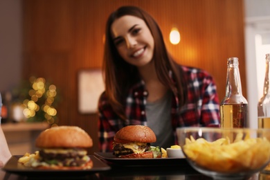 Photo of Young woman having lunch in cafe, focus on burger