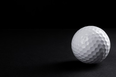 Golf ball on black background, space for text