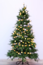 Photo of Blurred view of beautiful Christmas tree with fairy lights, indoors