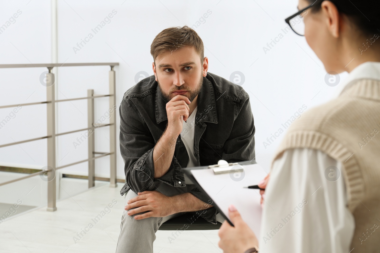 Photo of Psychotherapist working with drug addicted young man indoors