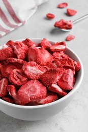 Photo of Bowl with dried strawberries on light grey table, closeup