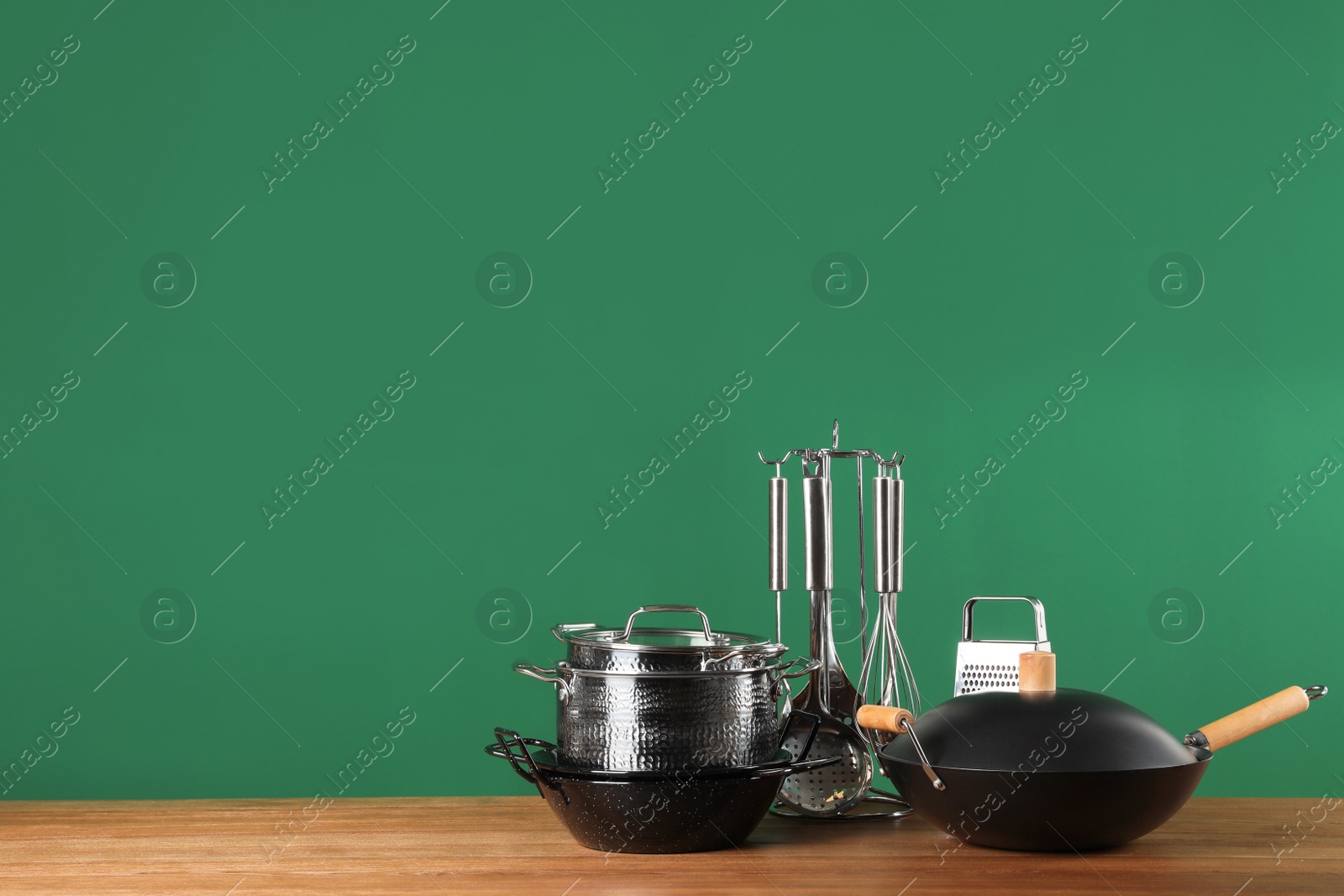 Photo of Set of clean cookware and utensils on table against color background. Space for text