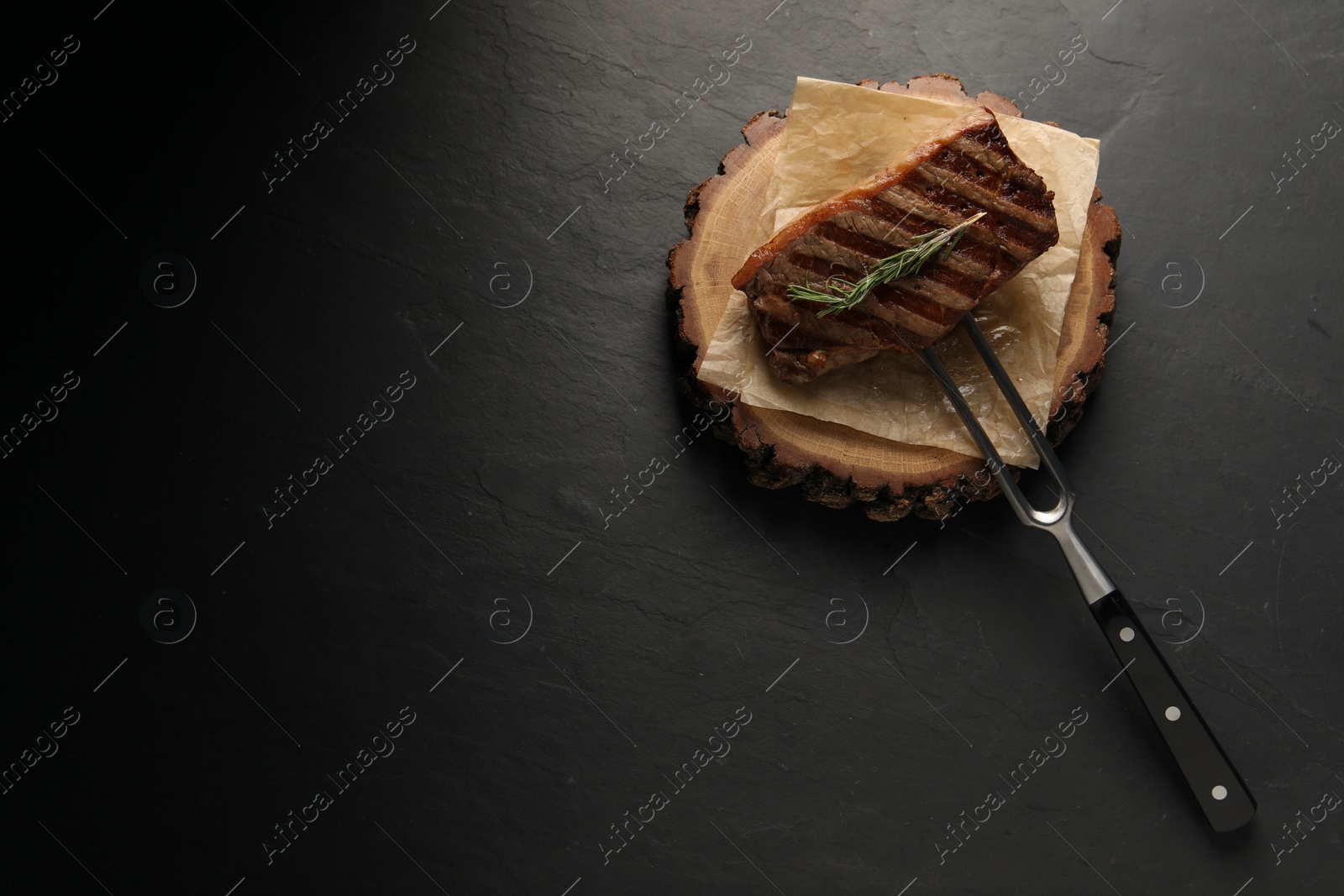Photo of Delicious grilled beef steak and rosemary on dark gray table, top view. Space for text