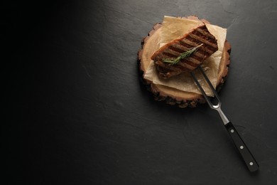 Delicious grilled beef steak and rosemary on dark gray table, top view. Space for text