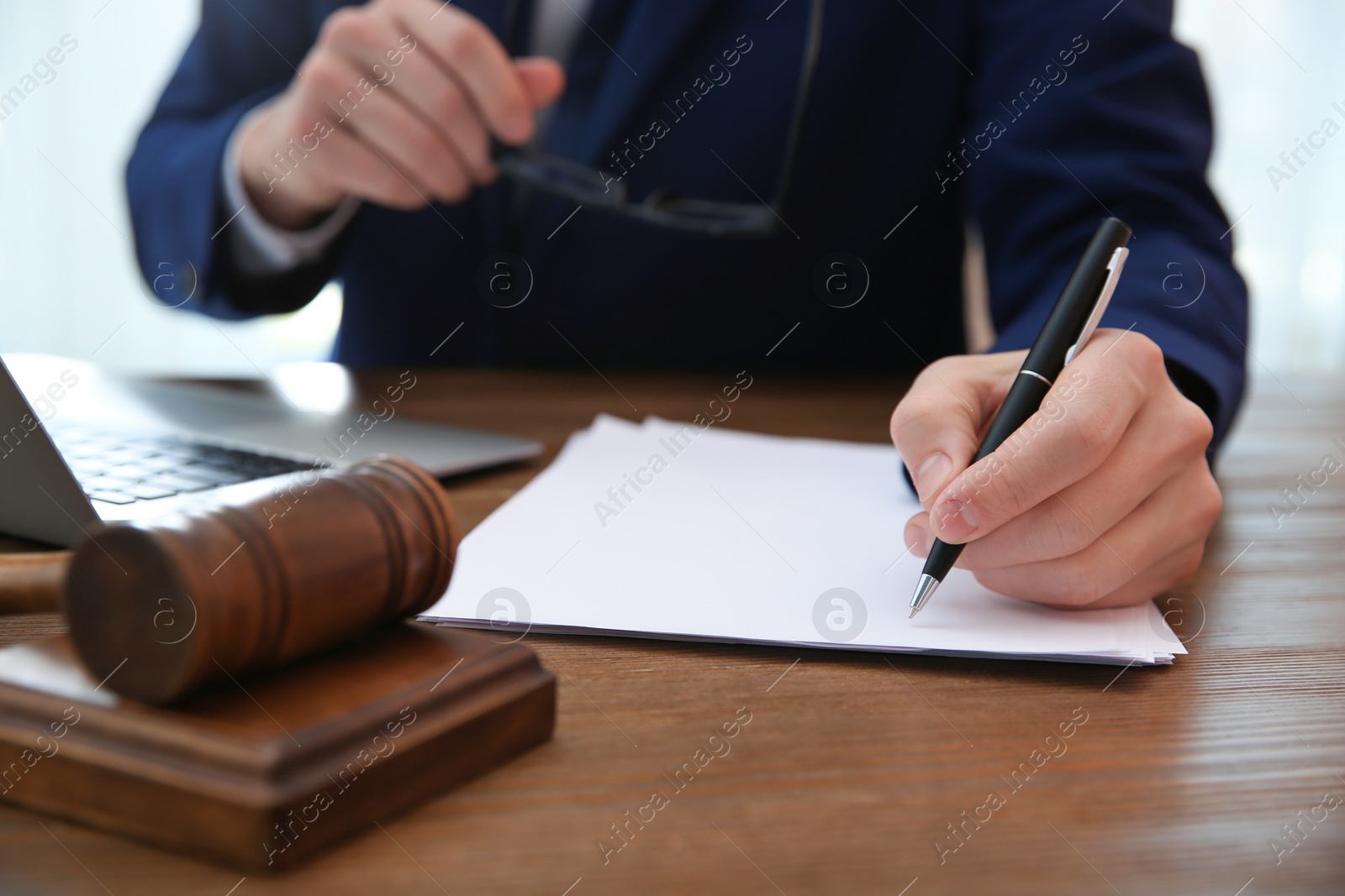 Photo of Notary working with papers and judge gavel on table, closeup. Law and justice concept