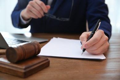 Notary working with papers and judge gavel on table, closeup. Law and justice concept