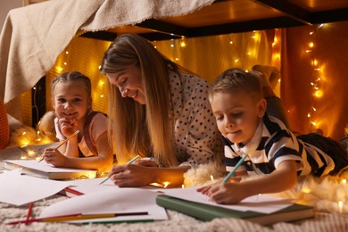 Photo of Mother and her children drawing in play tent at home