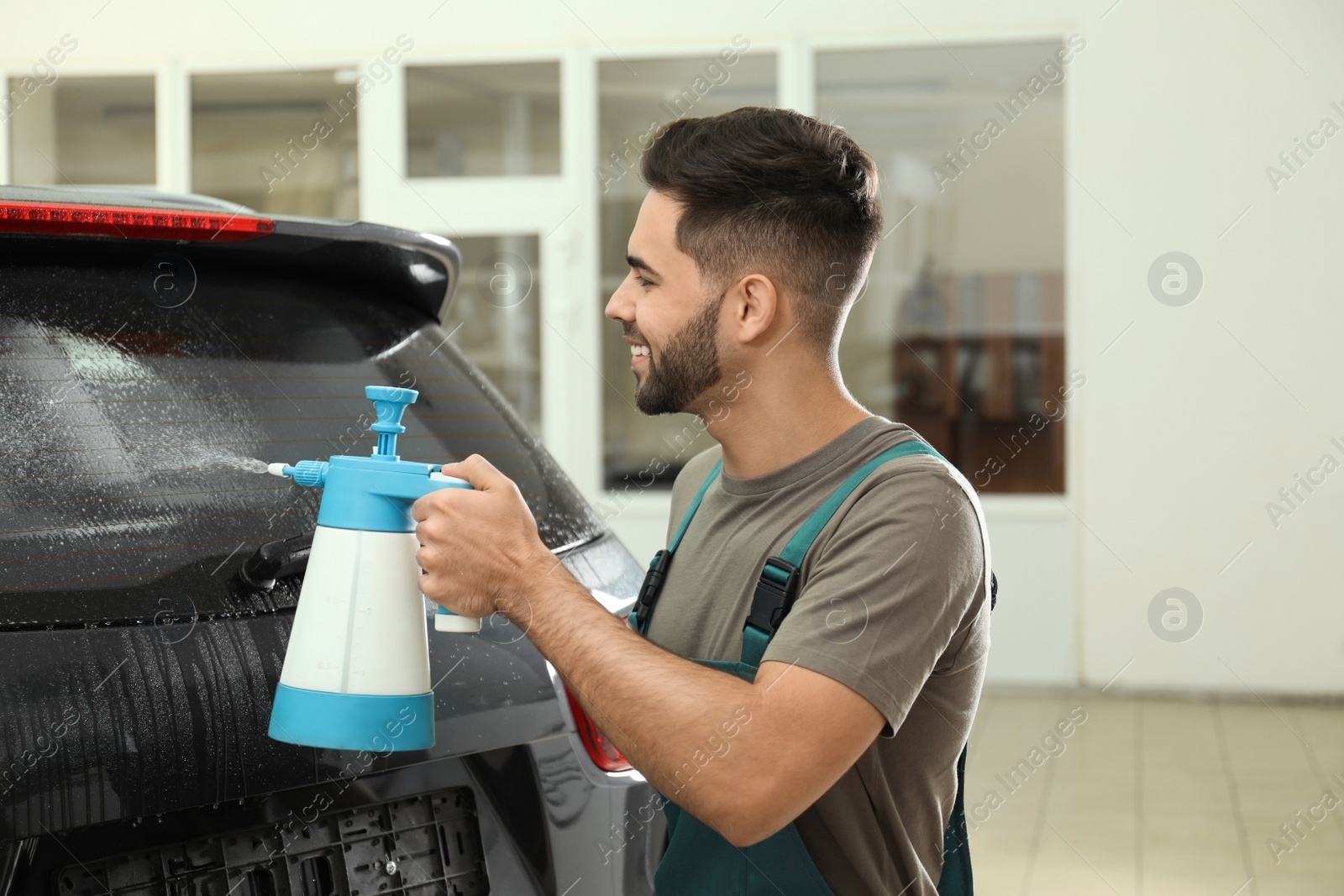 Photo of Worker spraying water onto car window before tinting