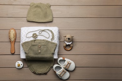 Photo of Flat lay composition with baby knitwear on wooden background, space for text. Cute photoshoot outfit