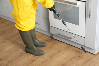 Photo of Pest control worker spraying pesticide in kitchen, closeup