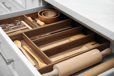 Open drawer of kitchen cabinet with different utensils, closeup