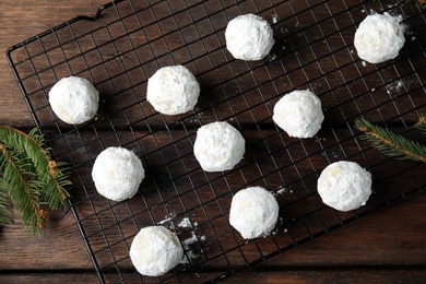 Photo of Christmas snowball cookies near fir tree branches on wooden table, flat lay
