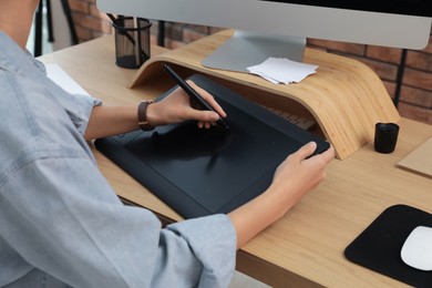 Professional retoucher working on graphic tablet at desk, closeup