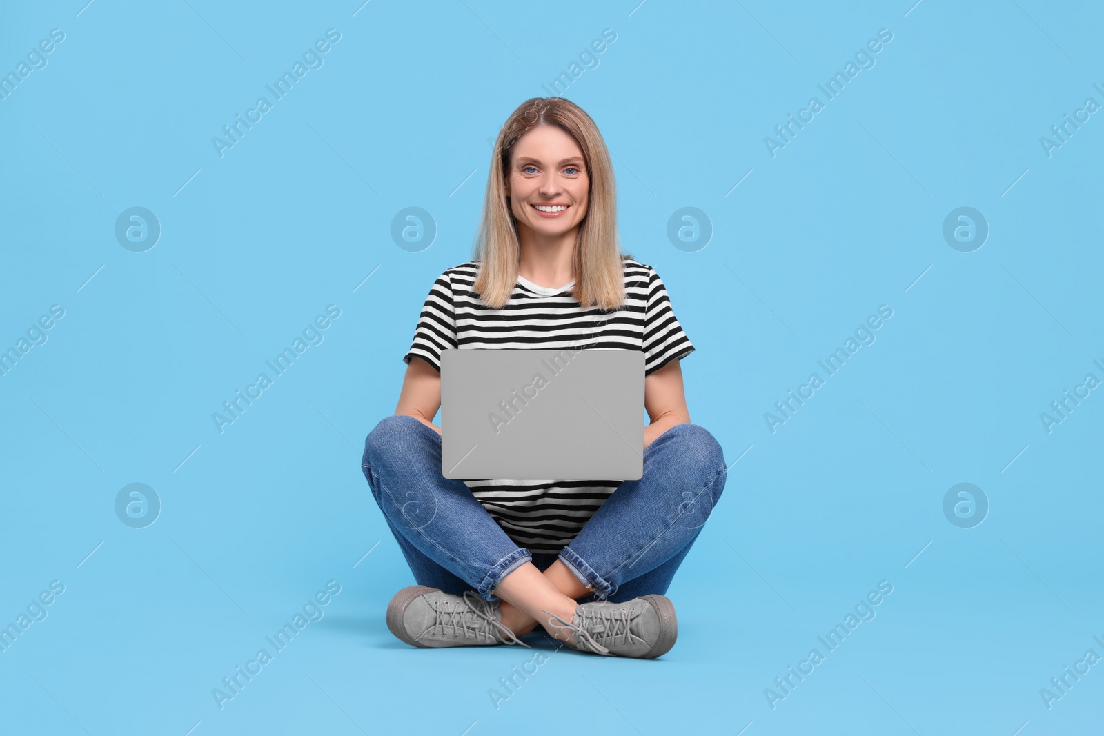 Photo of Happy woman with laptop on light blue background