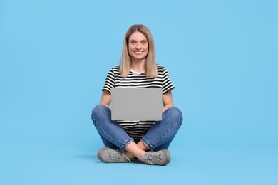 Happy woman with laptop on light blue background