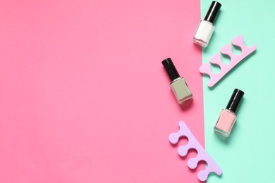Nail polishes and toe separators on color background, flat lay. Space for text