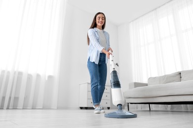 Photo of Woman cleaning floor with steam mop at home, low angle view