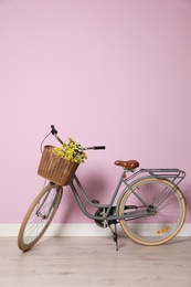 Retro bicycle with wicker basket near color wall