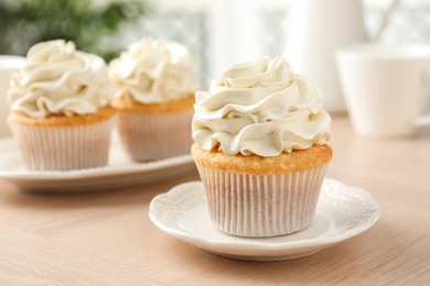 Tasty cupcakes with vanilla cream on light wooden table, closeup