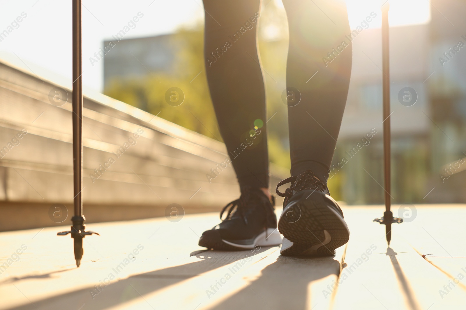 Photo of Woman practicing Nordic walking with poles outdoors on sunny day, closeup