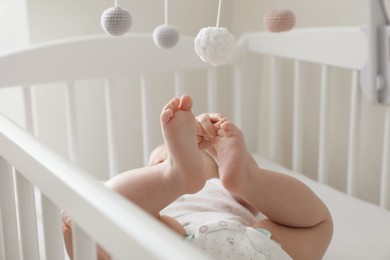 Cute little baby lying in comfortable crib at home