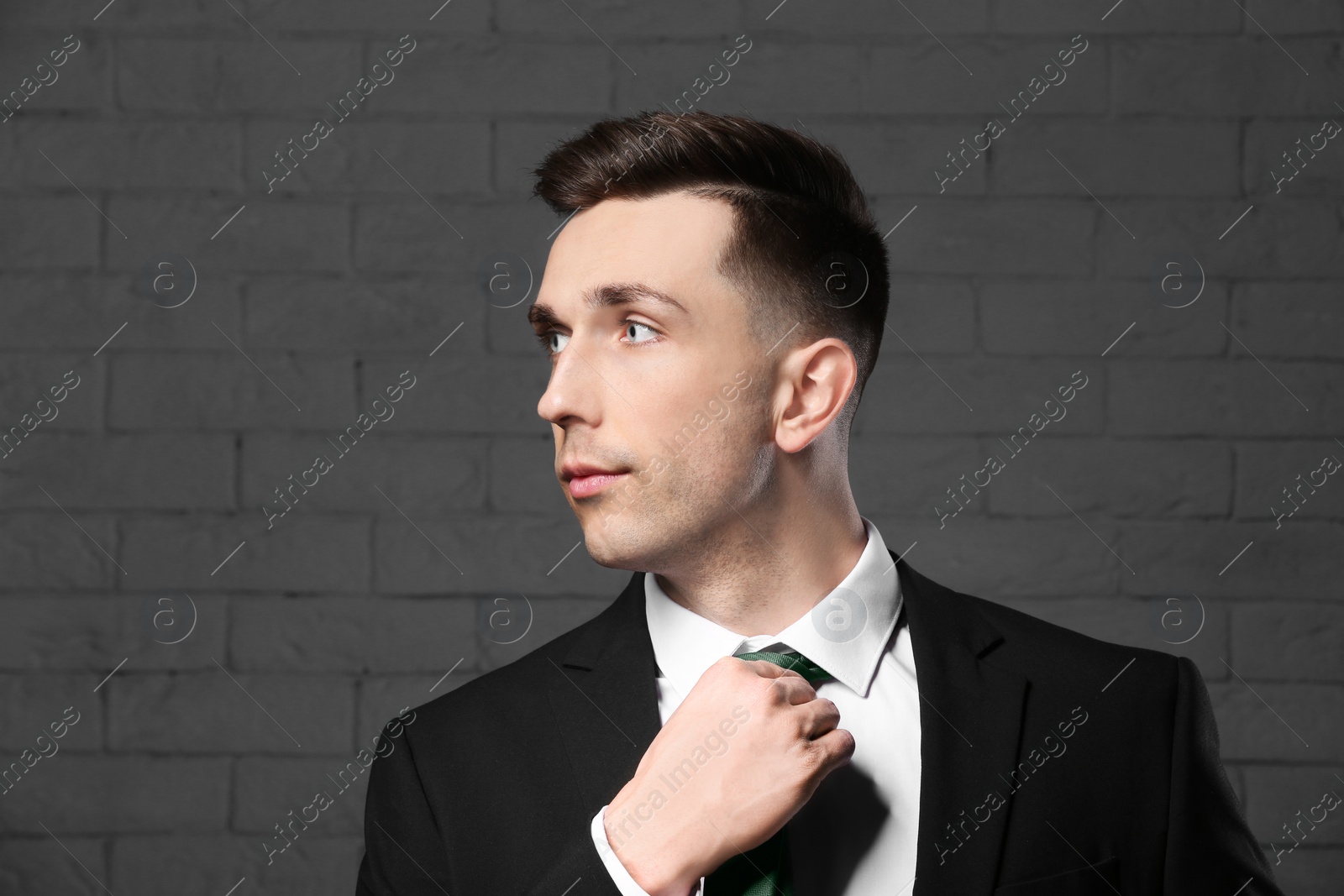 Photo of Portrait of young man with beautiful hair on brick wall background