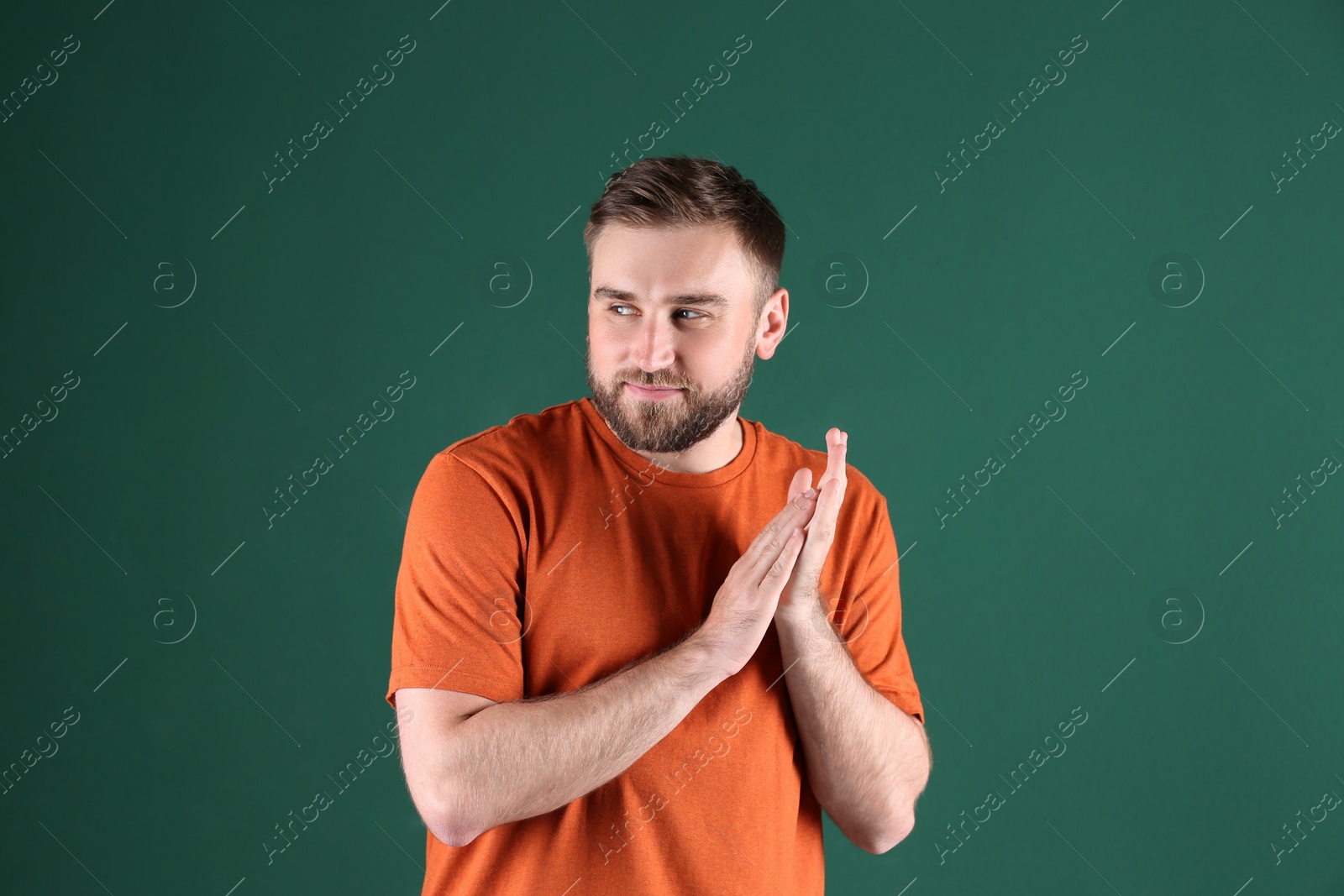 Photo of Greedy young man rubbing hands on green background