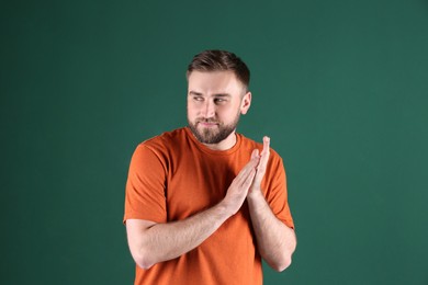 Photo of Greedy young man rubbing hands on green background
