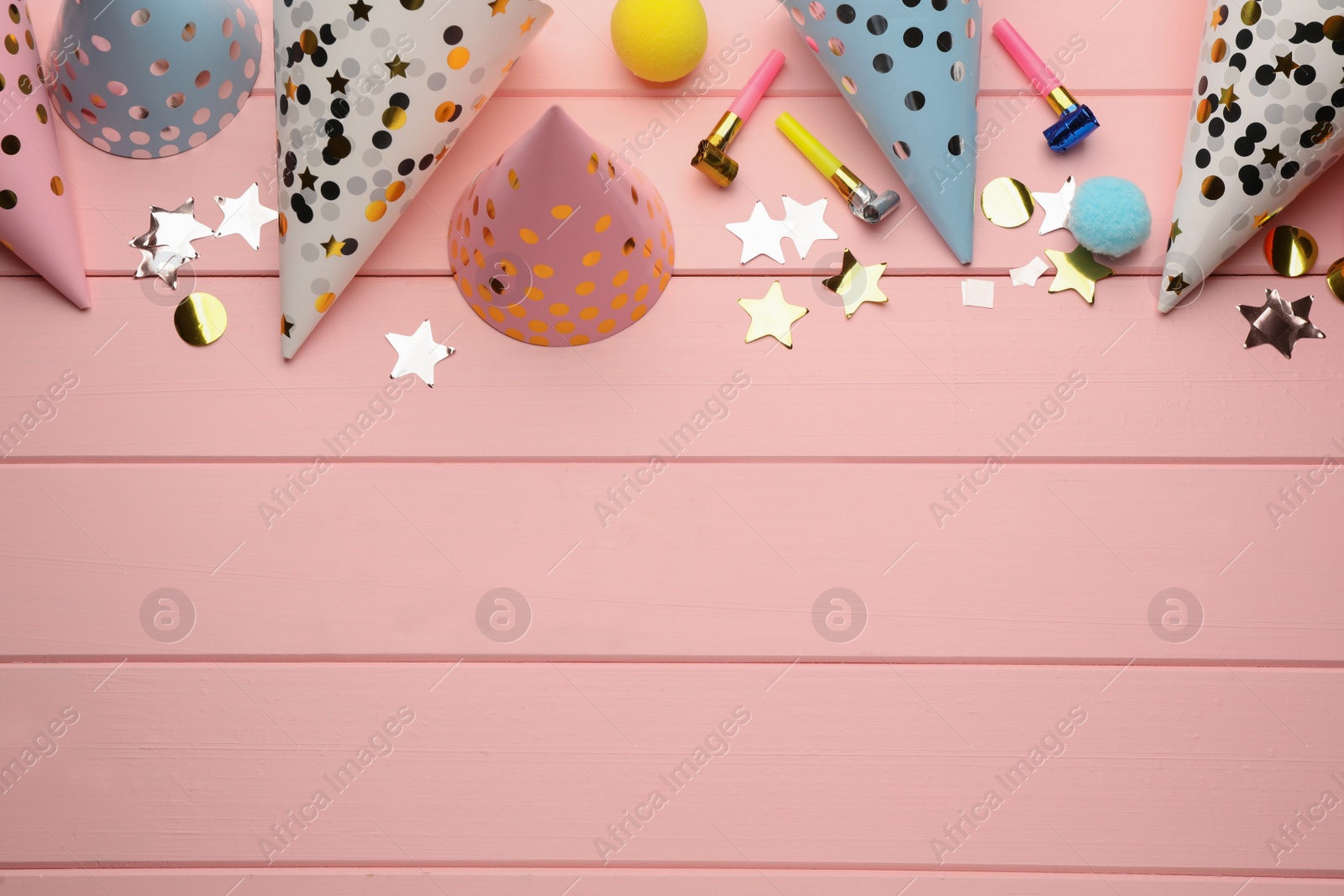 Photo of Flat lay composition with party hats and other festive items on pink wooden background. Space for text