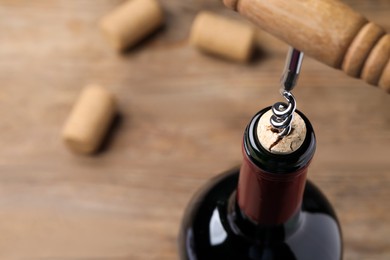 Opening wine bottle with corkscrew on table, closeup. Space for text