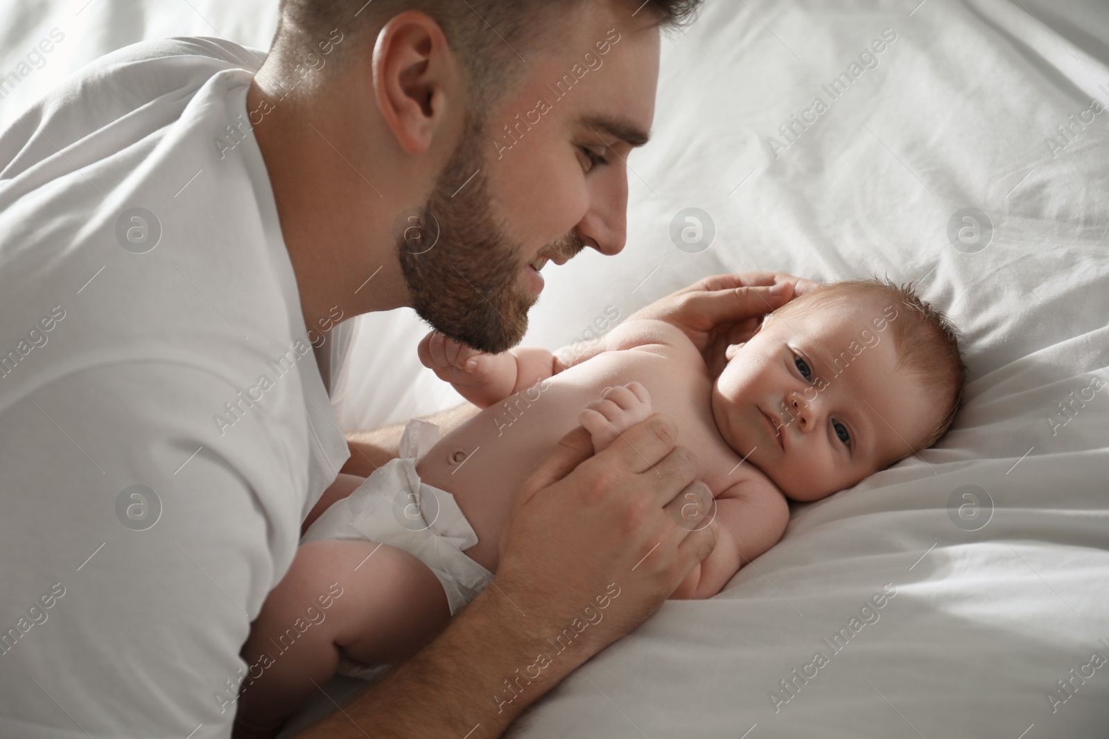 Photo of Father with his newborn son on bed