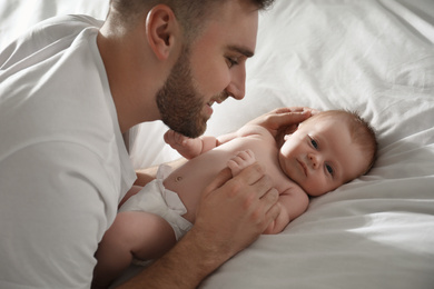 Photo of Father with his newborn son on bed