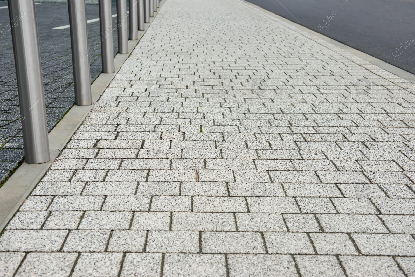 Photo of Stone sidewalk path near road on city street. Footpath covering