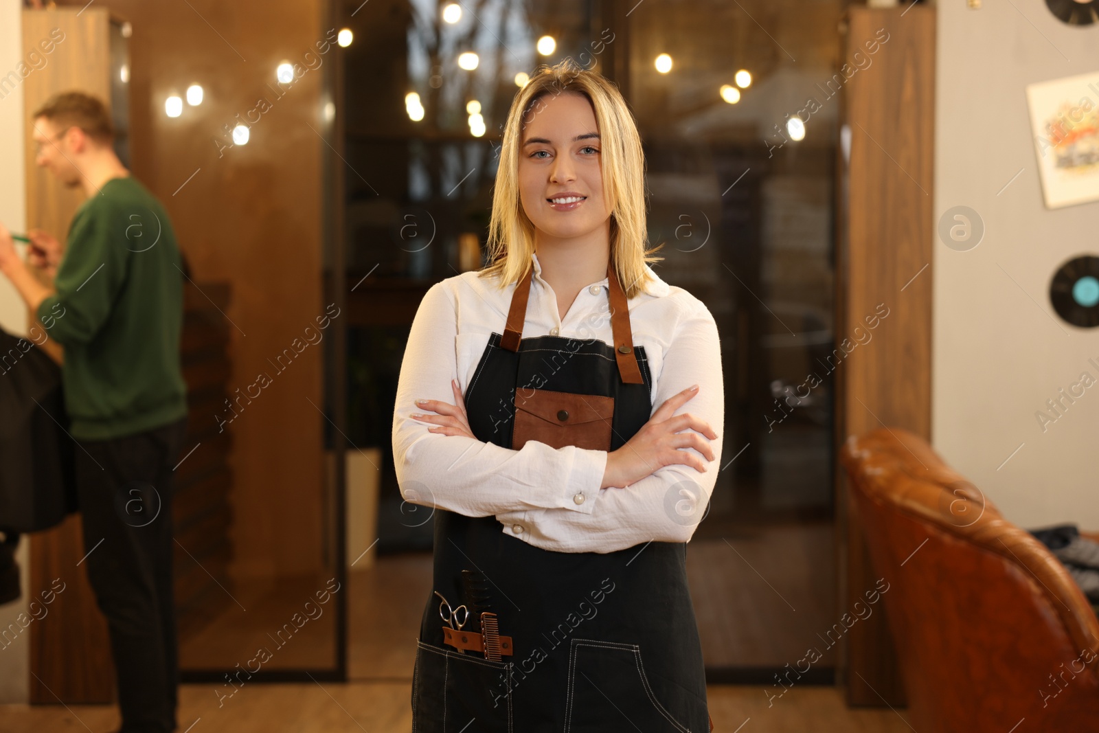 Photo of Portrait of professional hairdresser wearing apron in beauty salon