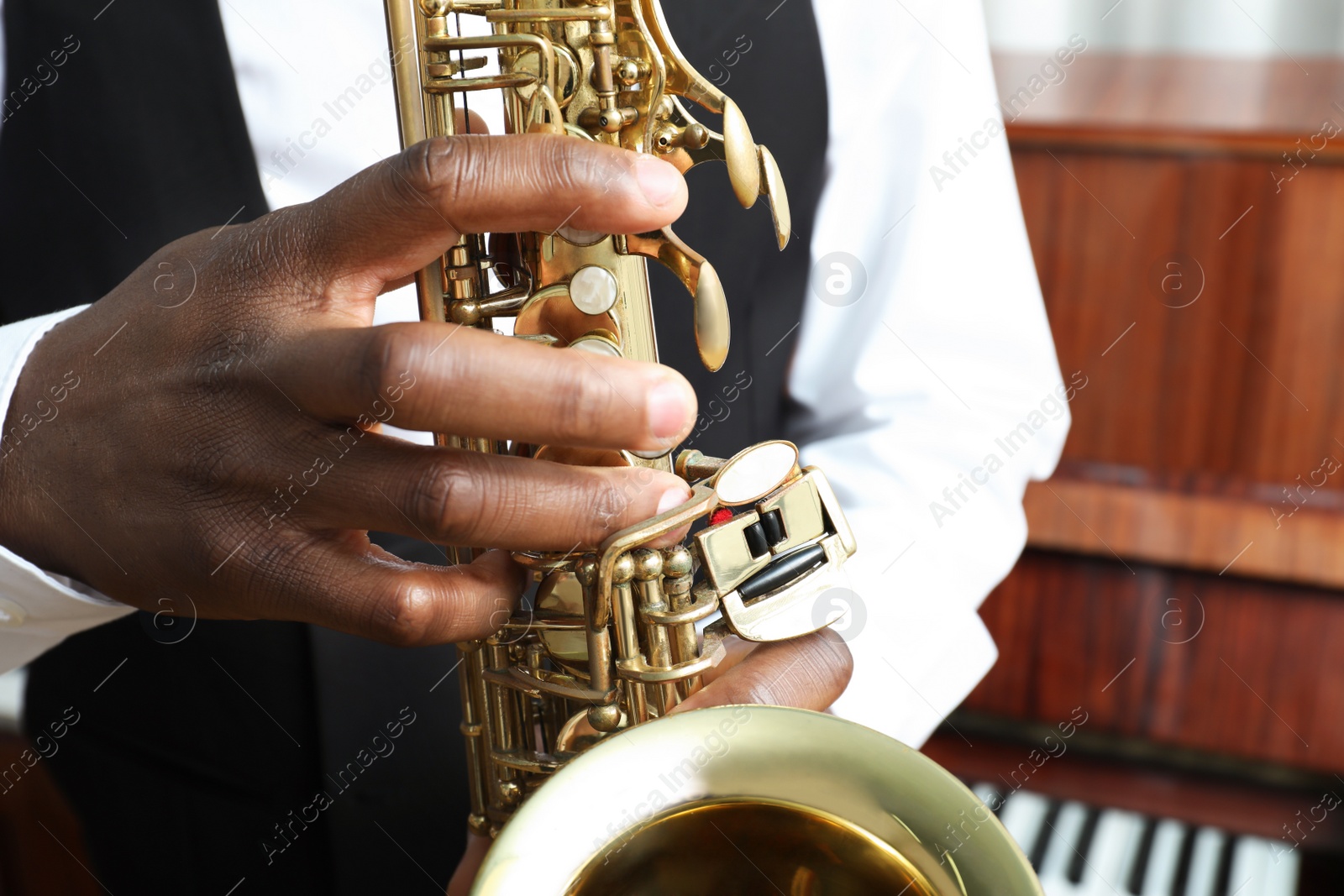 Photo of African-American man playing saxophone indoors, closeup. Talented musician