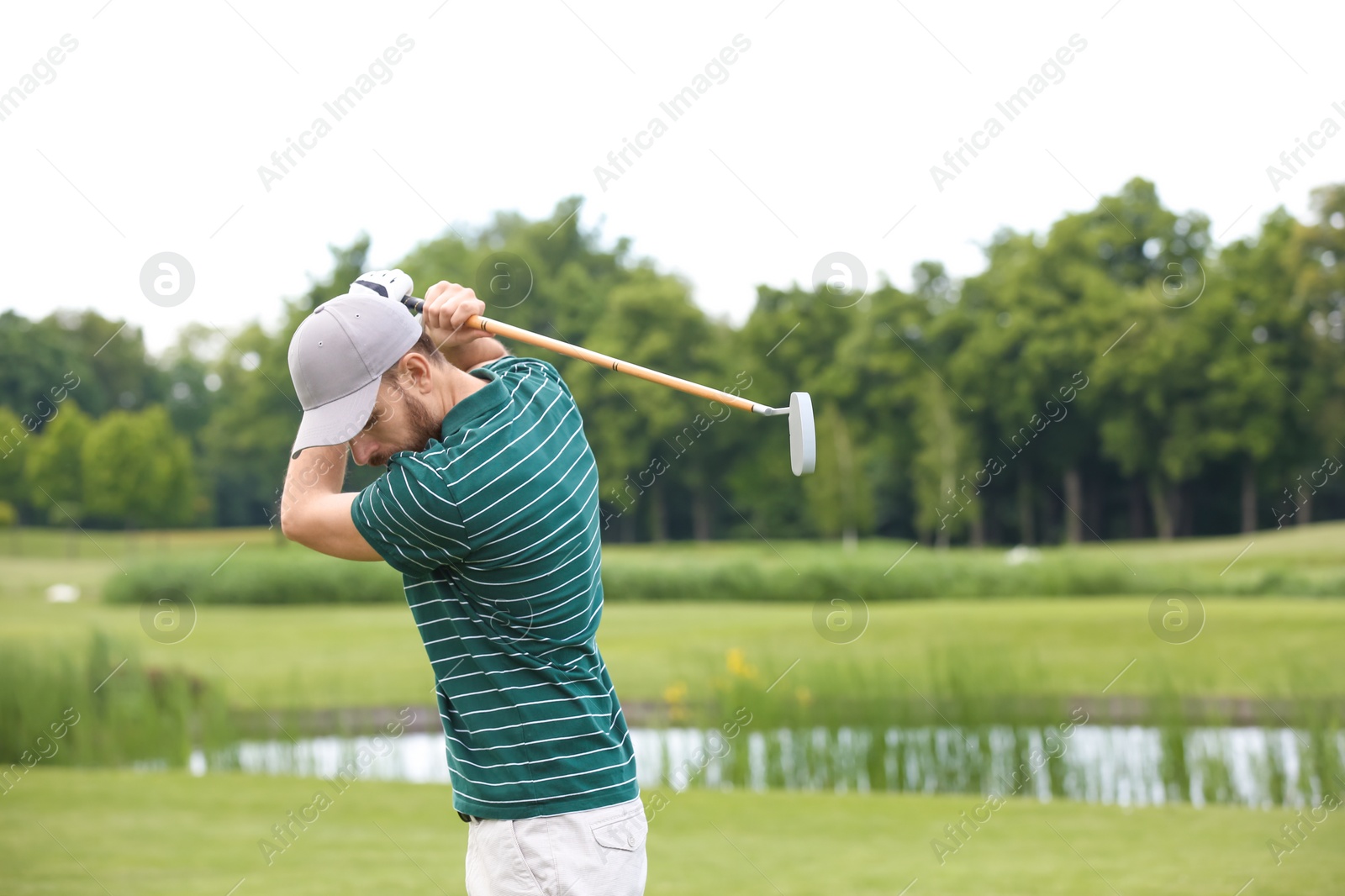 Photo of Man playing golf on green course. Sport and leisure